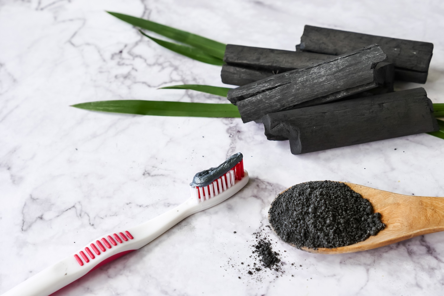 Charcoal toothpaste on a toothbrush with loose charcoal powder, illustrating the question is charcoal good for your teeth.