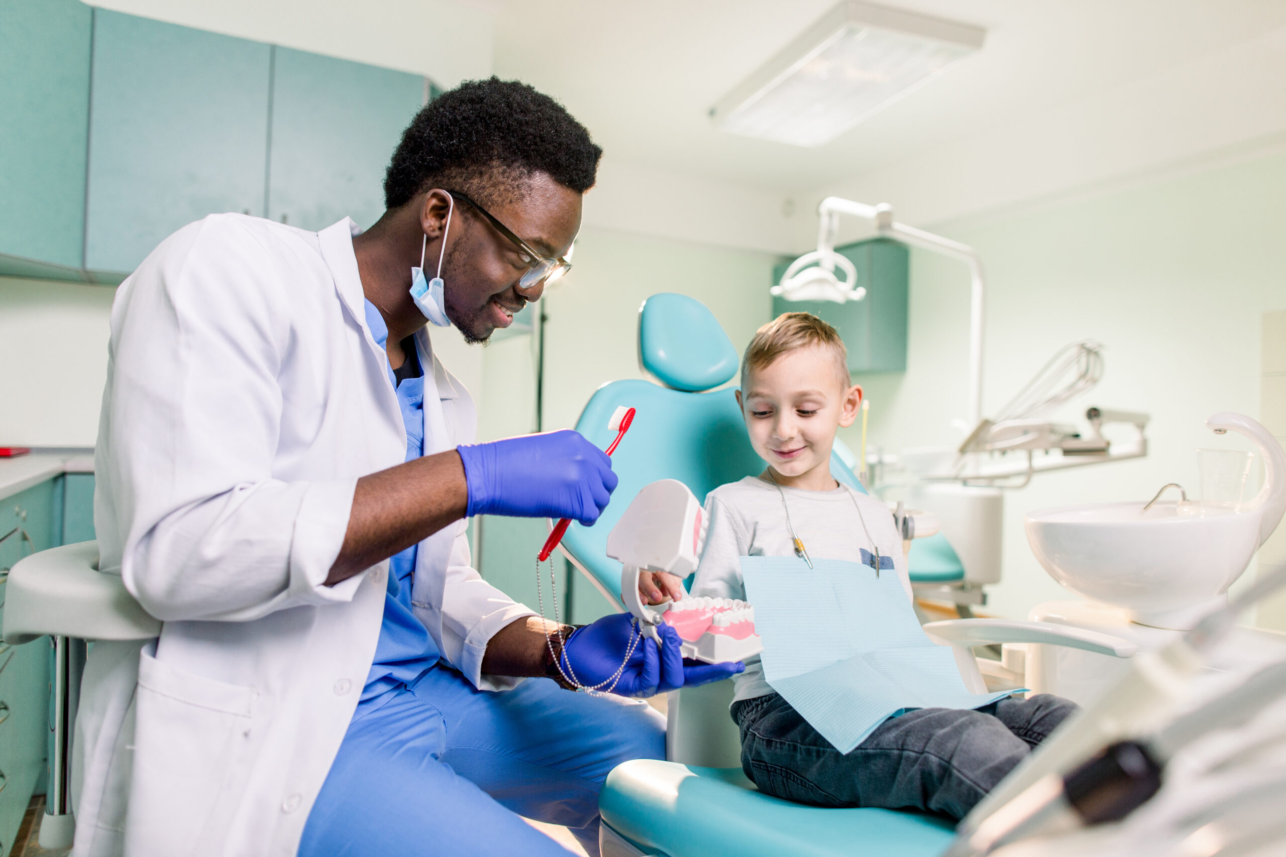 Friendly pediatric dental consultation at St. Louis County Dental showing a dentist using a model to teach a child about aesthetic oral health.