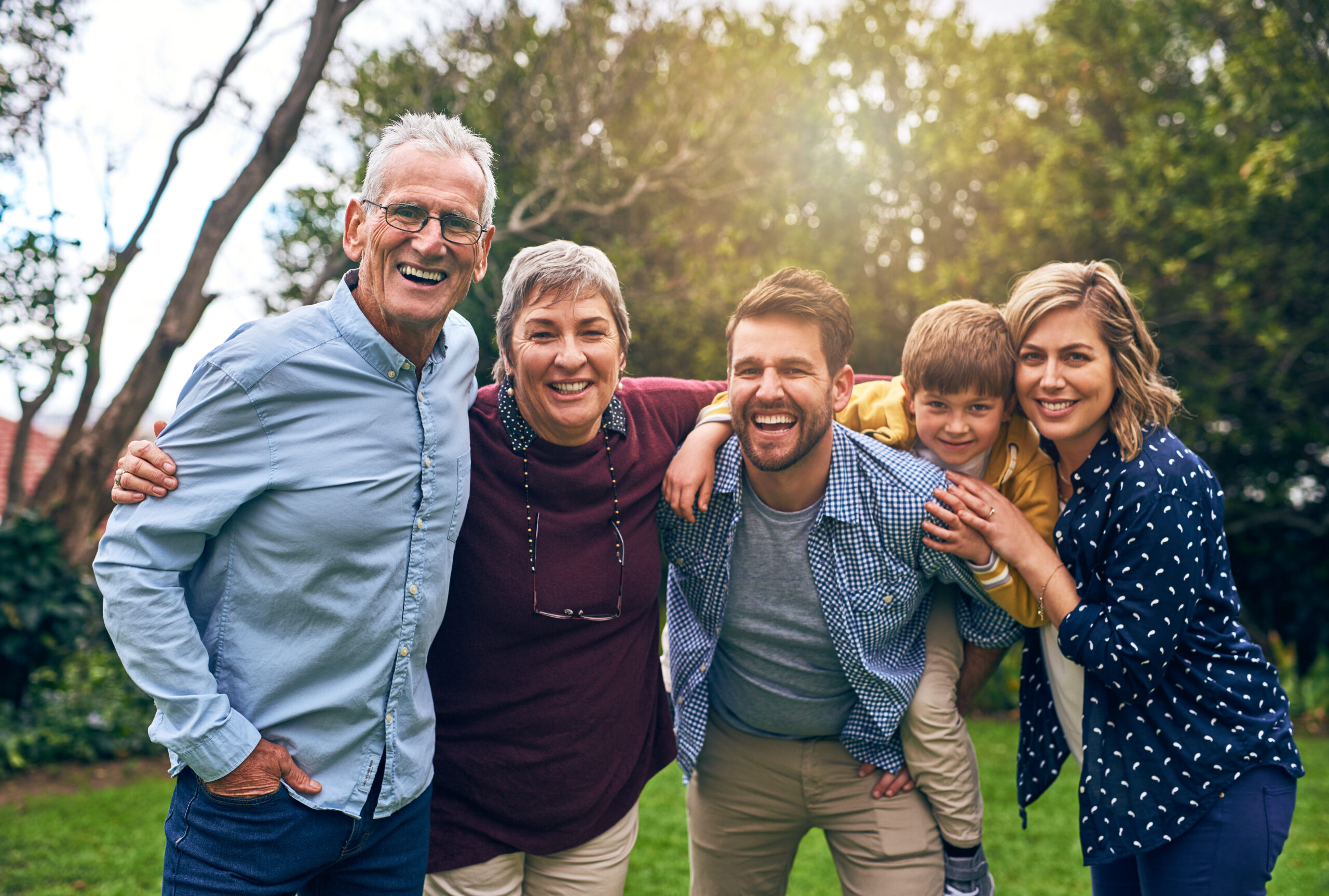 A multi-generational family smiling together outdoors, highlighting the benefits of aesthetic family dentistry services in St. Louis.