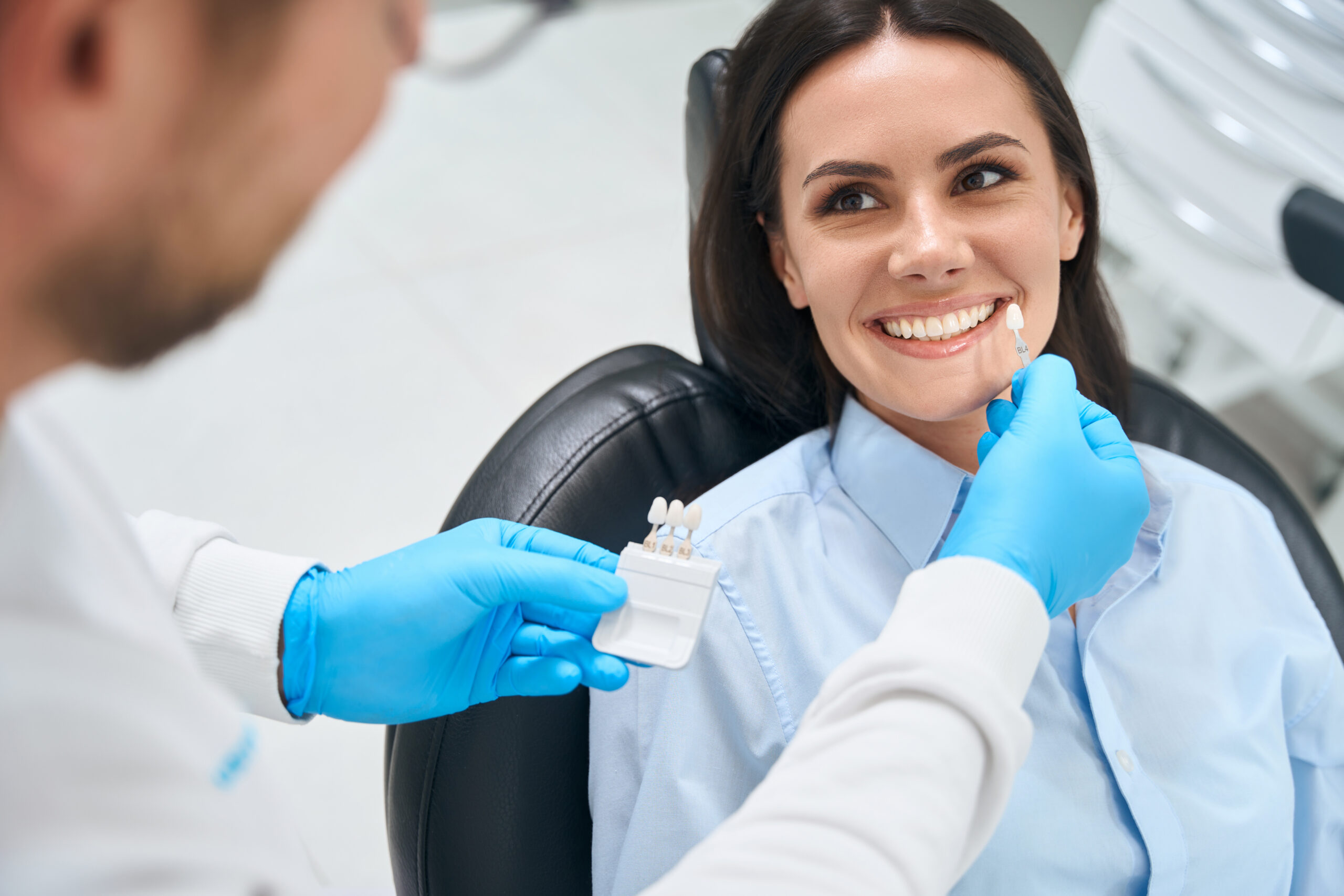 Cosmetic dentist in St. Louis showing veneer shade options to a patient during a consultation